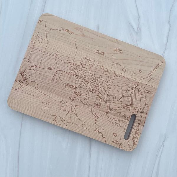 Pictured is a rectangular wood cutting board with the map of Ojai California engraved on it.