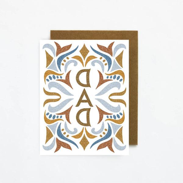 A card featuring the word dad surrounded by a festive pattern in light blue, brown and dark blue.