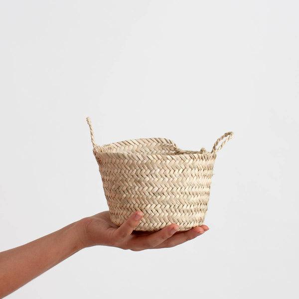 Tiny hand woven basket made from natural palm leaf with two small handles to carry it